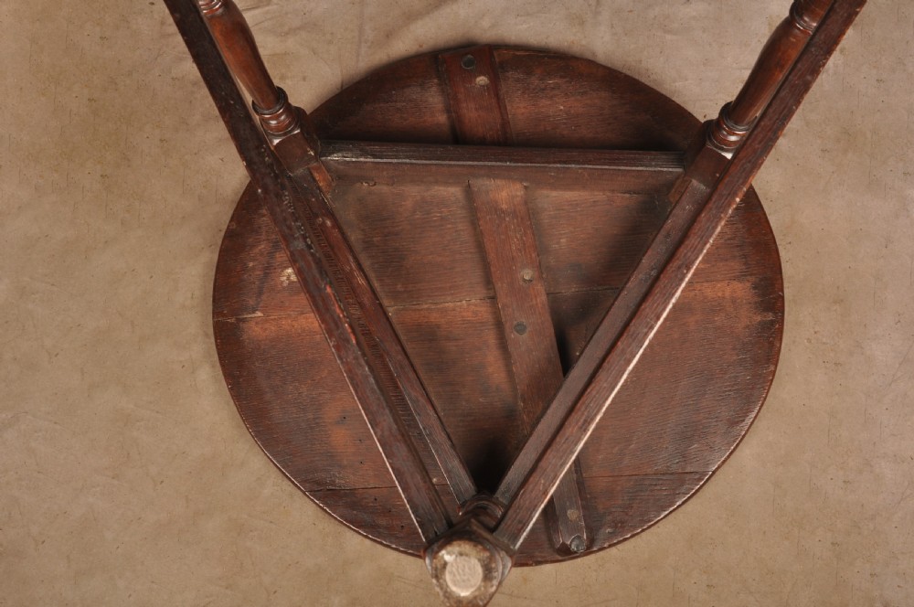 An 18th-century circular timber cricket table with three turned legs connected by a low triangular stretcher. View X