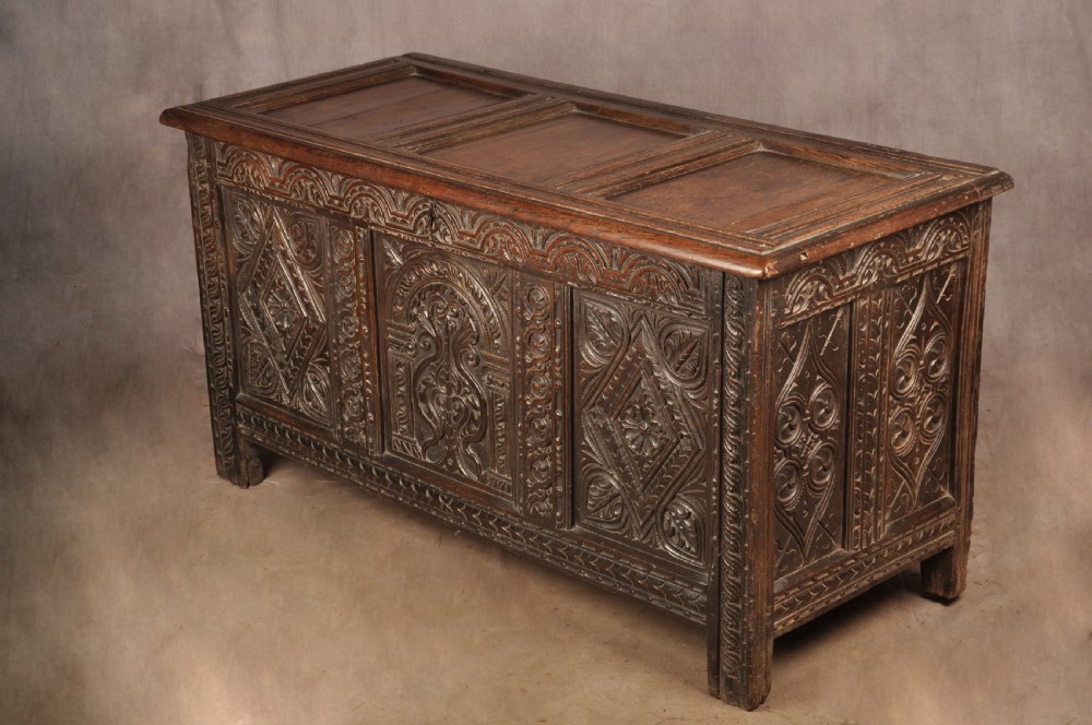 A 17th-century carved dark oak coffer featuring intricate geometric lozenge panels, an arched central carving, and a flat hinged lid. View III