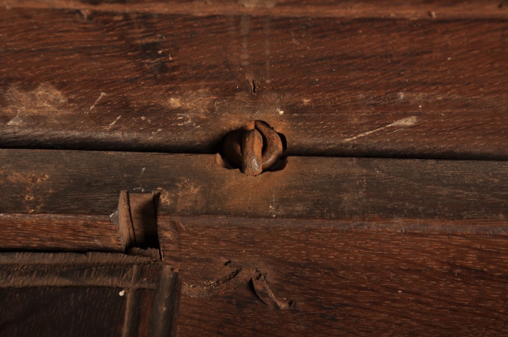 A 17th-century carved dark oak coffer featuring intricate geometric lozenge panels, an arched central carving, and a flat hinged lid. View XII