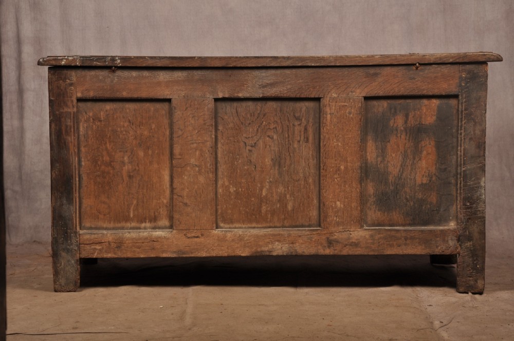 A 17th-century carved dark oak coffer featuring intricate geometric lozenge panels, an arched central carving, and a flat hinged lid. View XV