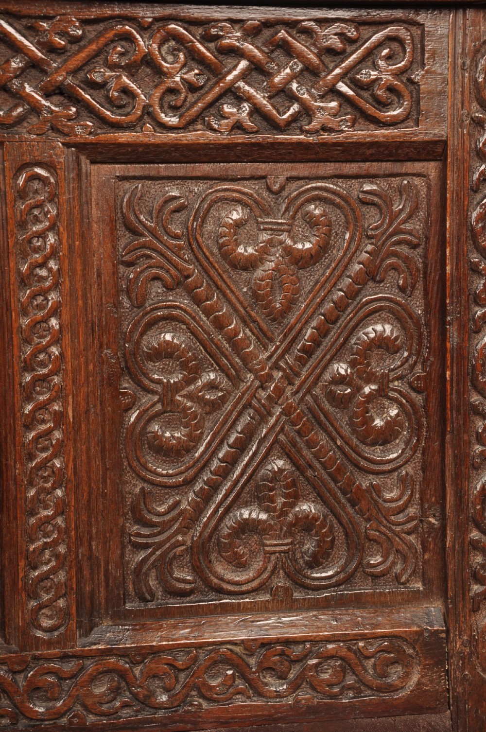 A dark oak 17th-century coffer featuring four carved relief panels, a carved top frieze with an inscribed date, and a hinged lid. View III