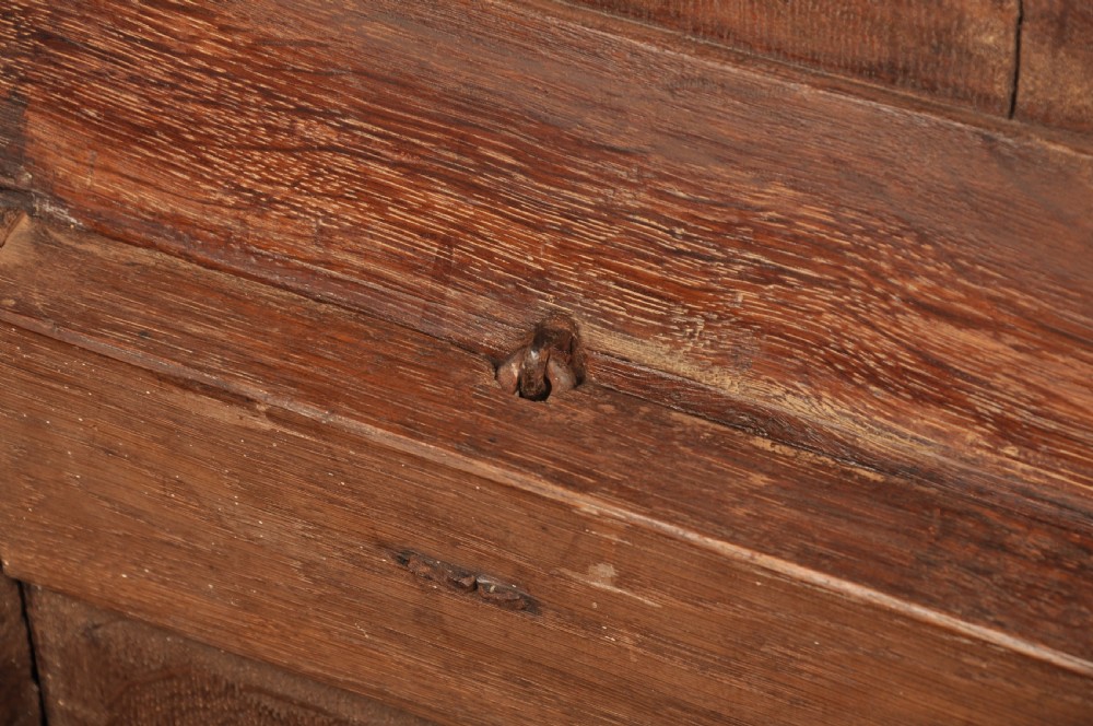A dark oak 17th-century coffer featuring four carved relief panels, a carved top frieze with an inscribed date, and a hinged lid. View XI