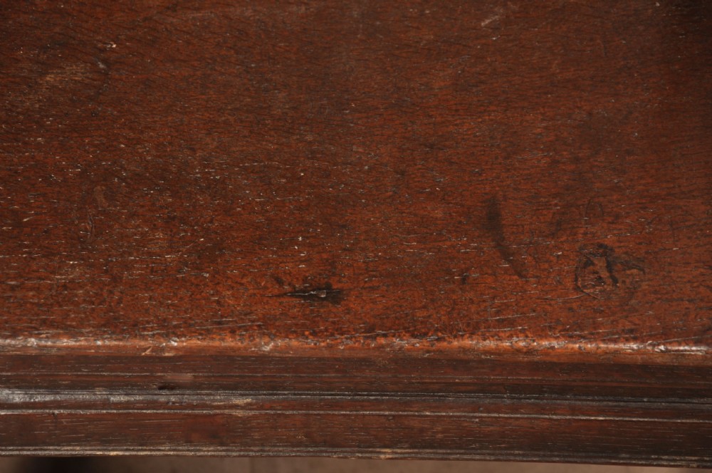 A 17th-century dark oak wainscot armchair featuring a carved scrolled cresting rail, a lozenge-carved back panel, turned front legs, and a solid wooden seat. View XI