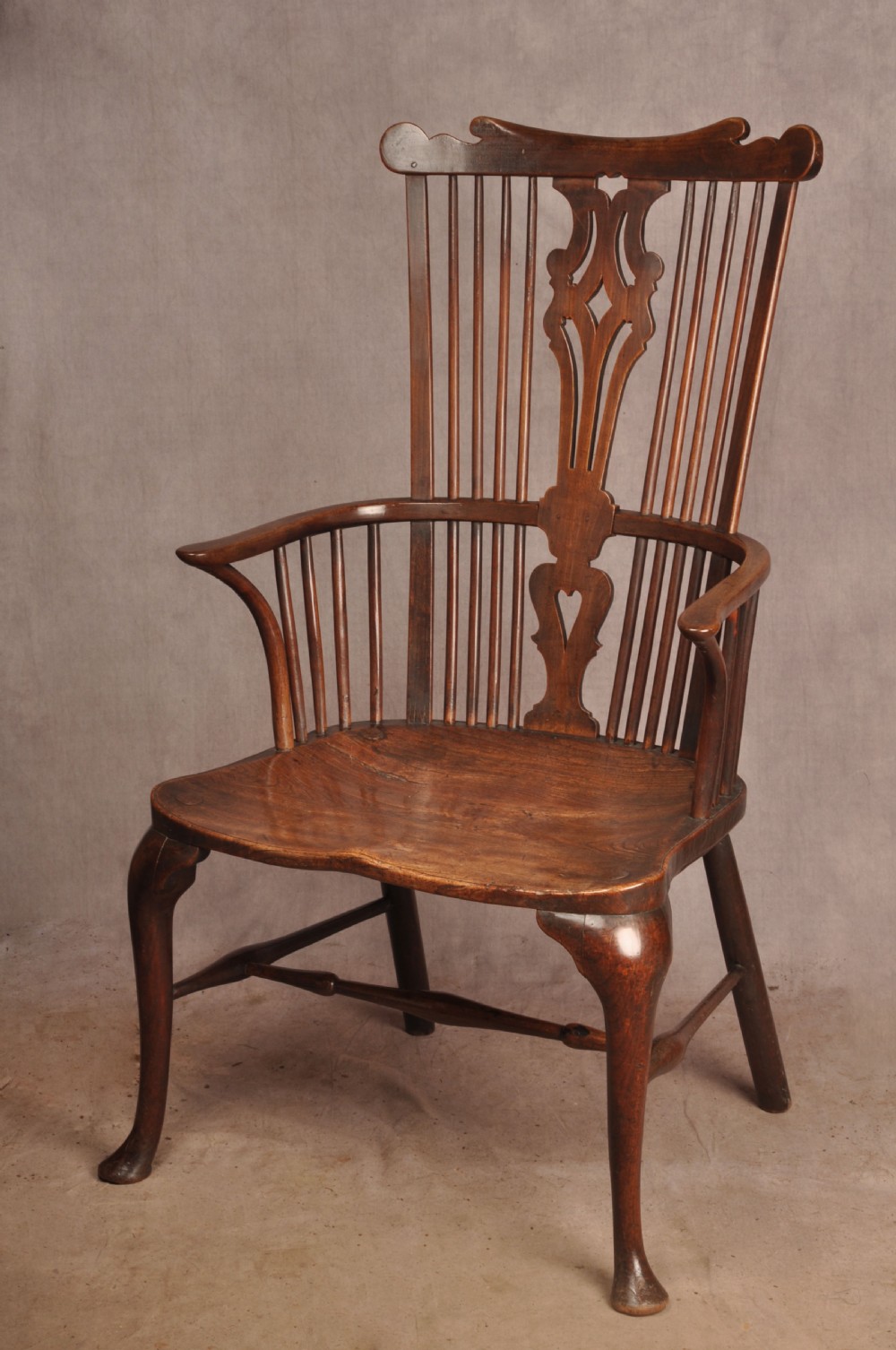 An 18th-century cherrywood Thames Valley Windsor armchair featuring a high comb back, pierced fretwork splat, curved armrests, saddled seat, and cabriole front legs. View II
