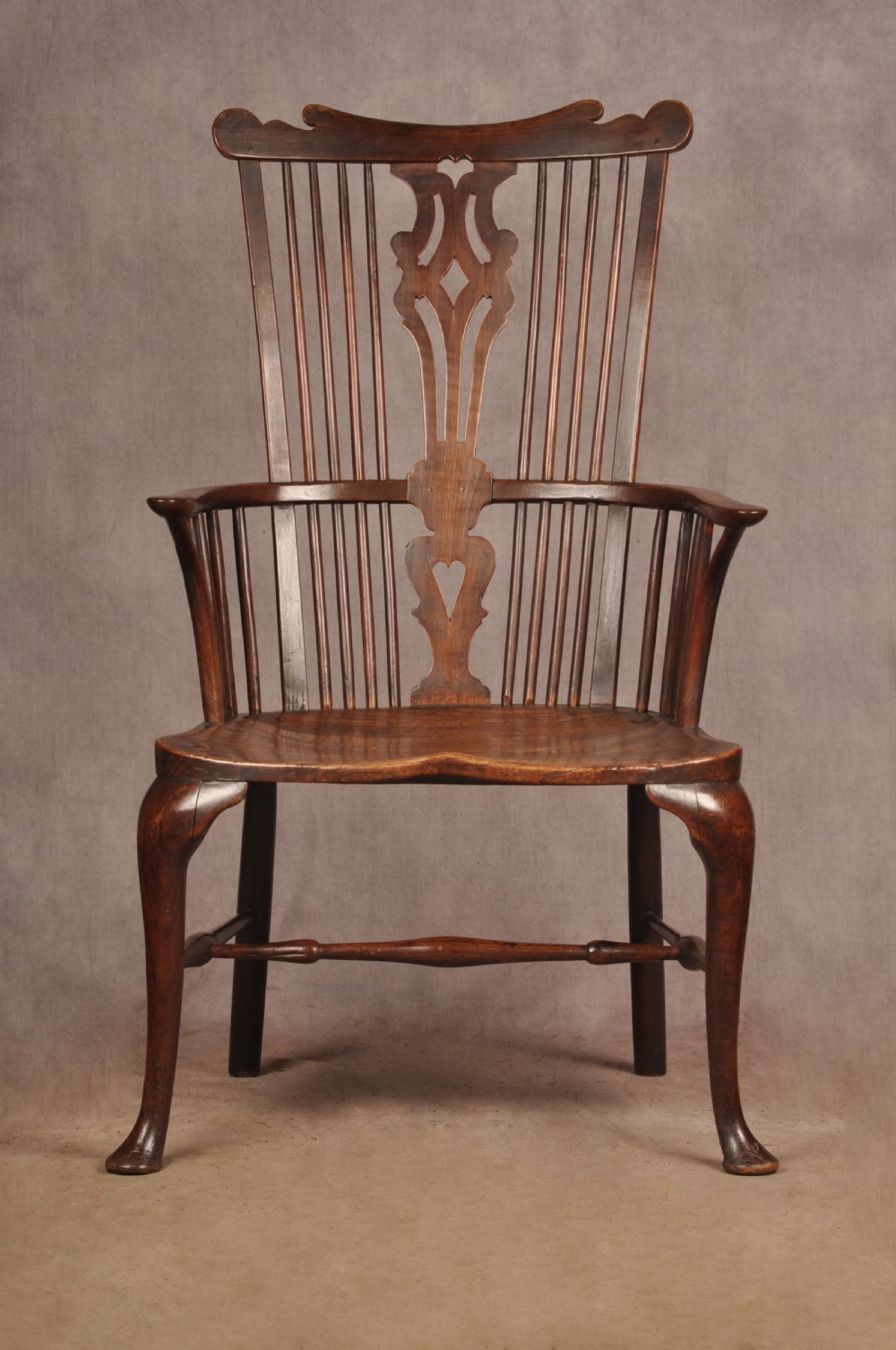 An 18th-century cherrywood Thames Valley Windsor armchair featuring a high comb back, pierced fretwork splat, curved armrests, saddled seat, and cabriole front legs. View V