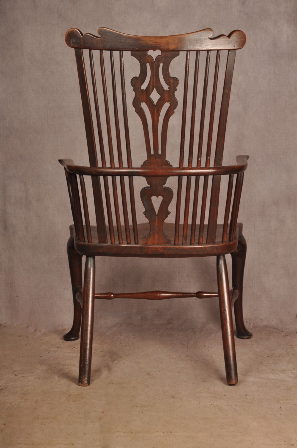 An 18th-century cherrywood Thames Valley Windsor armchair featuring a high comb back, pierced fretwork splat, curved armrests, saddled seat, and cabriole front legs. View XIV