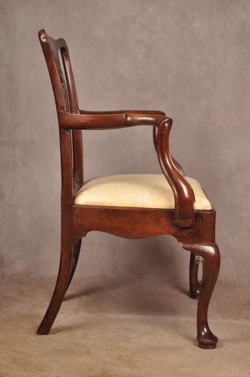 A George II mahogany armchair featuring a pierced back splat, swept armrests, a cream fabric seat, and cabriole front legs. View X