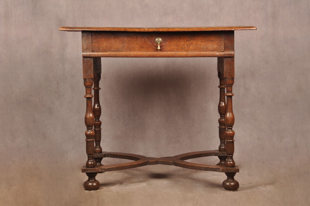 A 17th-century oak side table featuring baluster-turned legs, a shaped X-stretcher, a single frieze drawer with a brass drop handle, and a rectangular timber top. View IV
