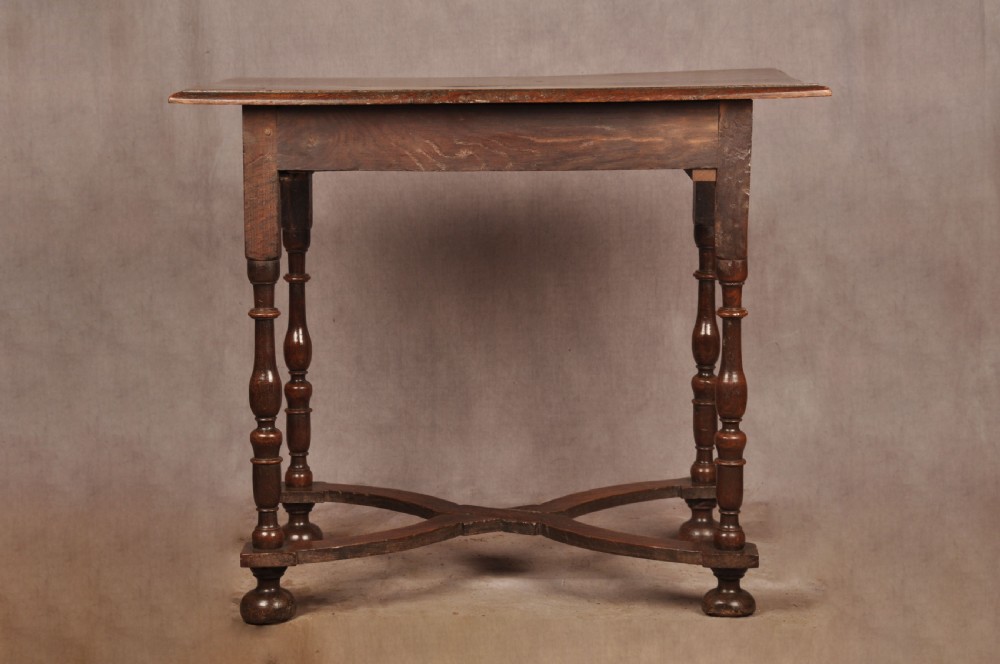 A 17th-century oak side table featuring baluster-turned legs, a shaped X-stretcher, a single frieze drawer with a brass drop handle, and a rectangular timber top. View XII