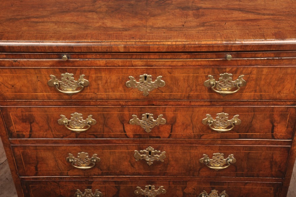 A George II walnut chest of drawers featuring four graduated drawers with brass handles and escutcheons, resting on bracket feet. View VIII