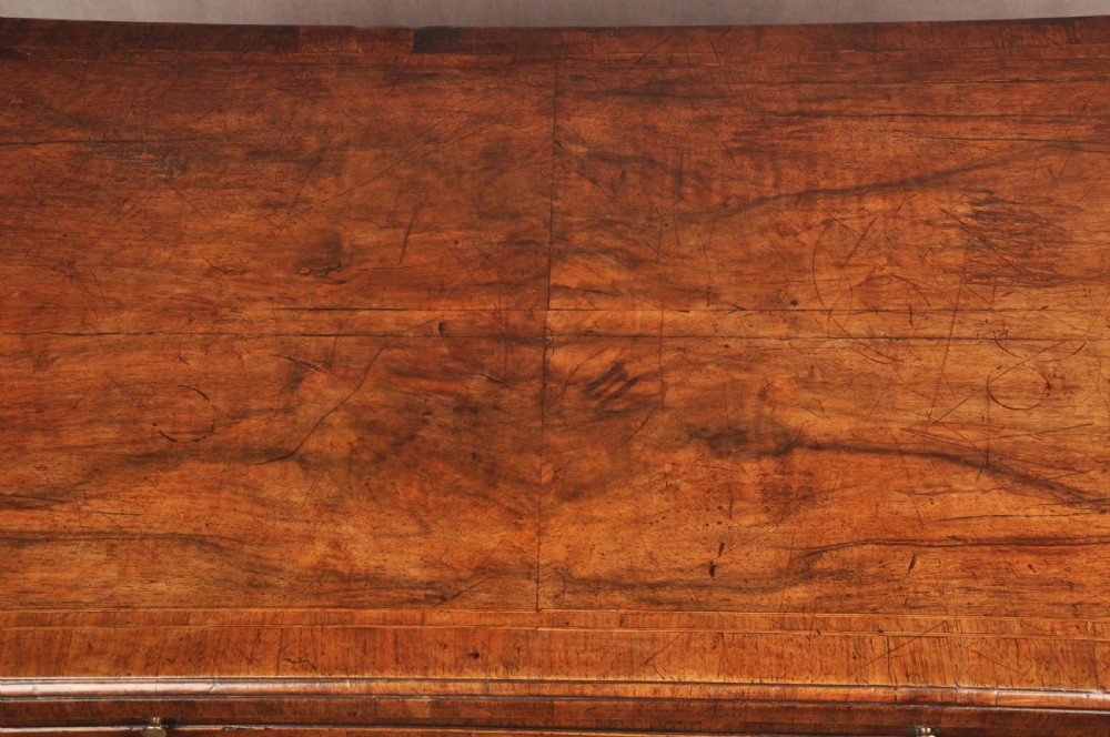 A George II walnut chest of drawers featuring four graduated drawers with brass handles and escutcheons, resting on bracket feet. View IX