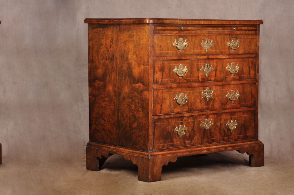 A George II walnut chest of drawers featuring four graduated drawers with brass handles and escutcheons, resting on bracket feet. View X