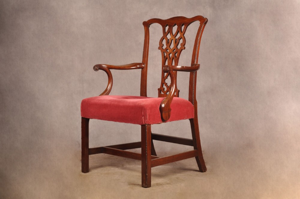 An 18th-century Chippendale style mahogany armchair featuring a pierced lattice splat back, curved arms, square legs with stretchers, and a red upholstered seat.