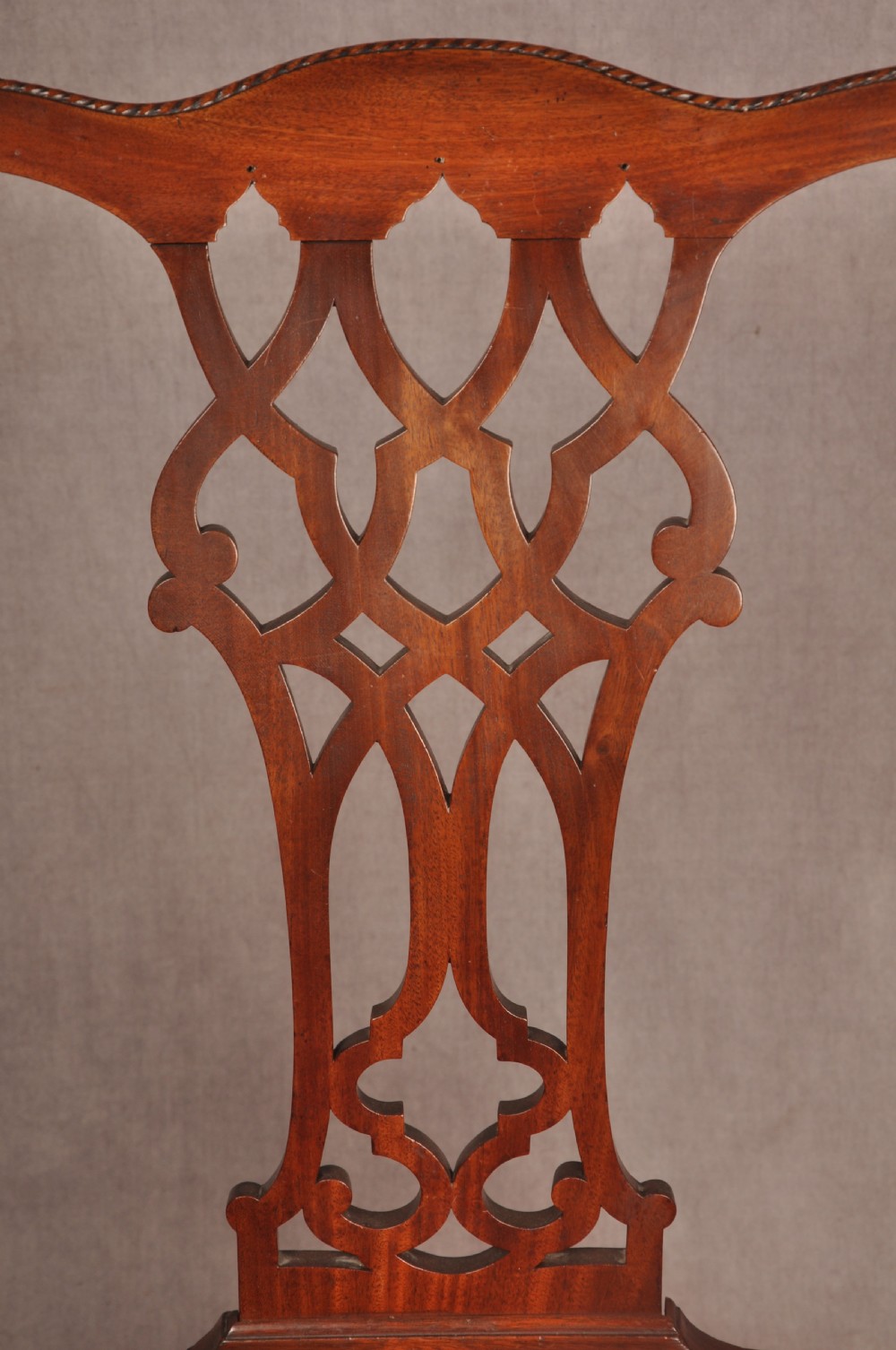 An 18th-century Chippendale style mahogany armchair featuring a pierced lattice splat back, curved arms, square legs with stretchers, and a red upholstered seat. View IV