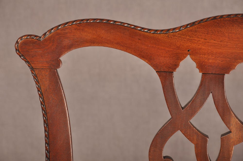 An 18th-century Chippendale style mahogany armchair featuring a pierced lattice splat back, curved arms, square legs with stretchers, and a red upholstered seat. View V