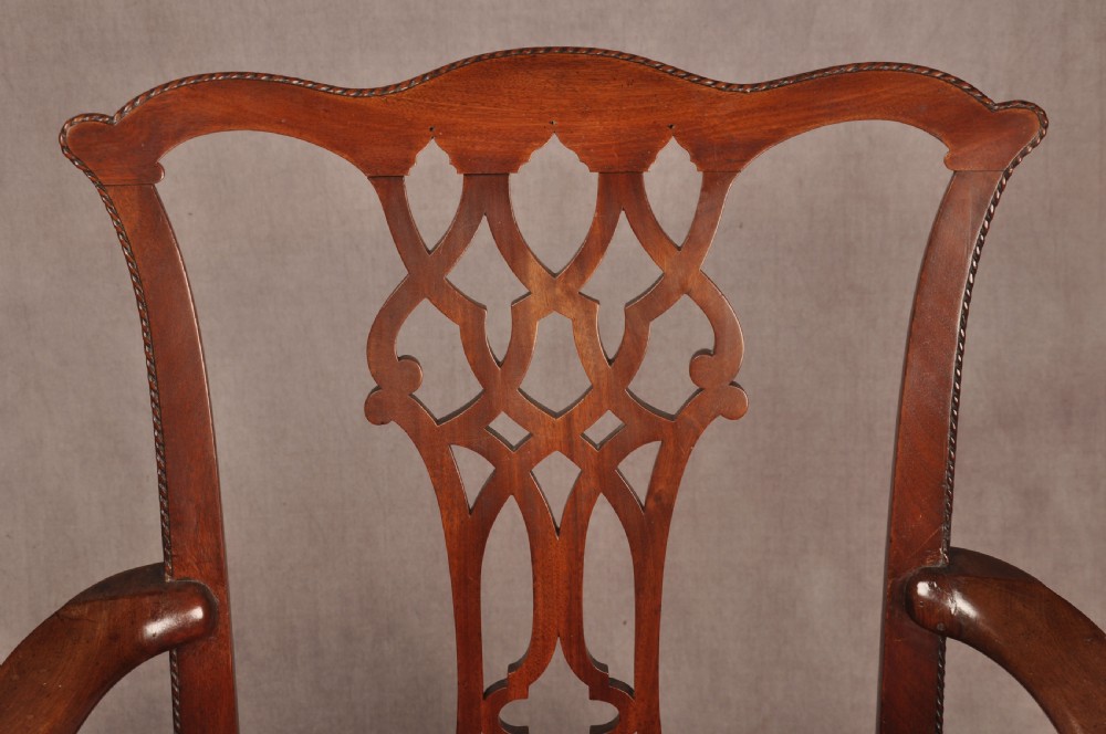 An 18th-century Chippendale style mahogany armchair featuring a pierced lattice splat back, curved arms, square legs with stretchers, and a red upholstered seat. View VI