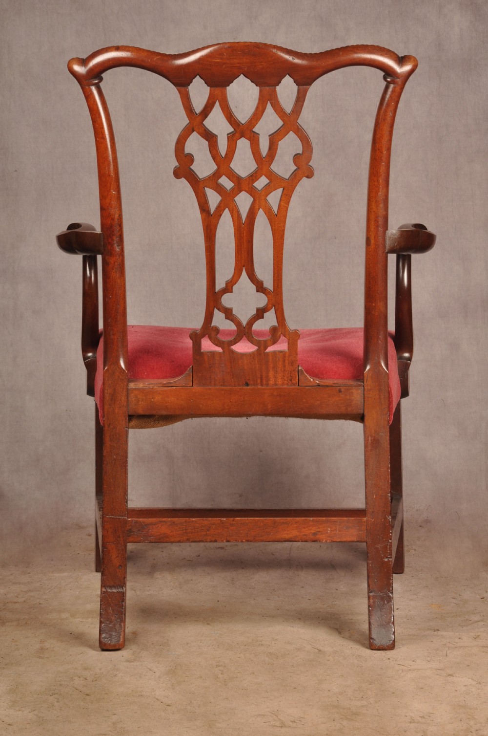 An 18th-century Chippendale style mahogany armchair featuring a pierced lattice splat back, curved arms, square legs with stretchers, and a red upholstered seat. View IX