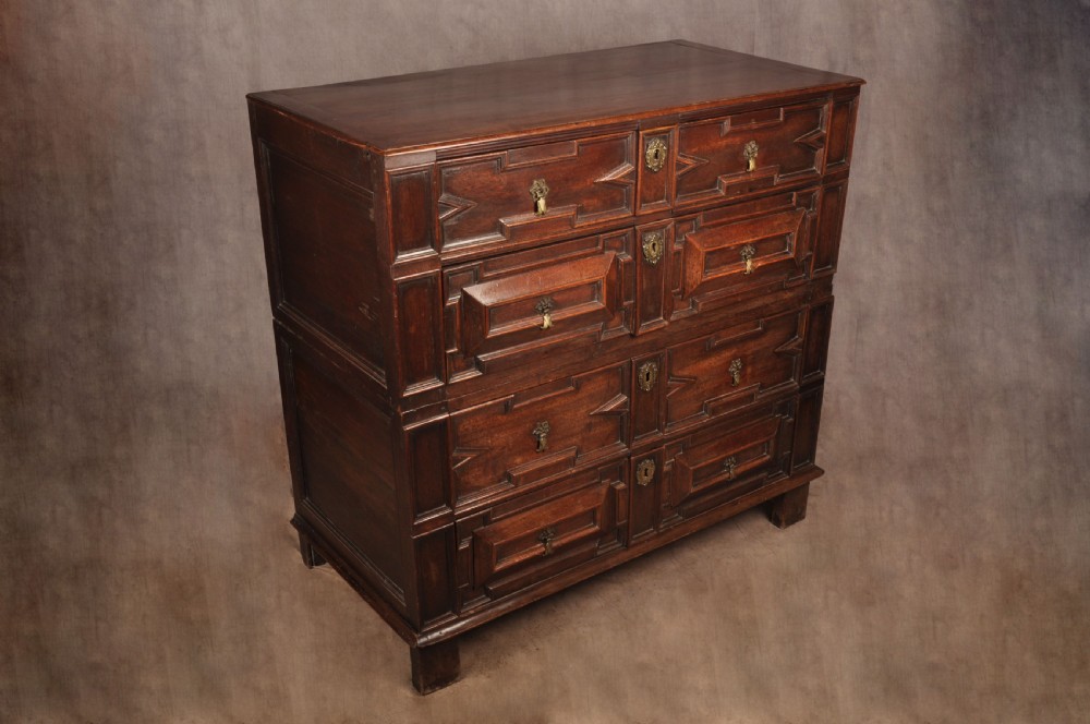 A 17th-century Charles II walnut and fruitwood chest of drawers featuring geometric mitred panels and brass keyhole escutcheons. View II