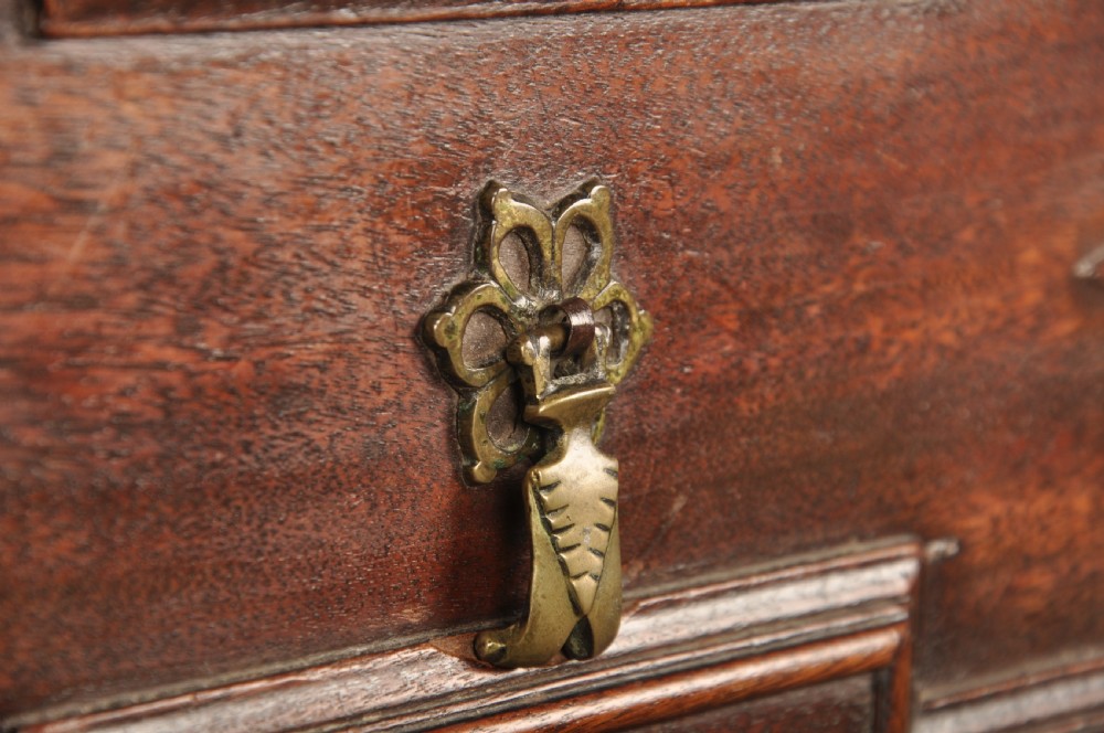 A 17th-century Charles II walnut and fruitwood chest of drawers featuring geometric mitred panels and brass keyhole escutcheons. View VI