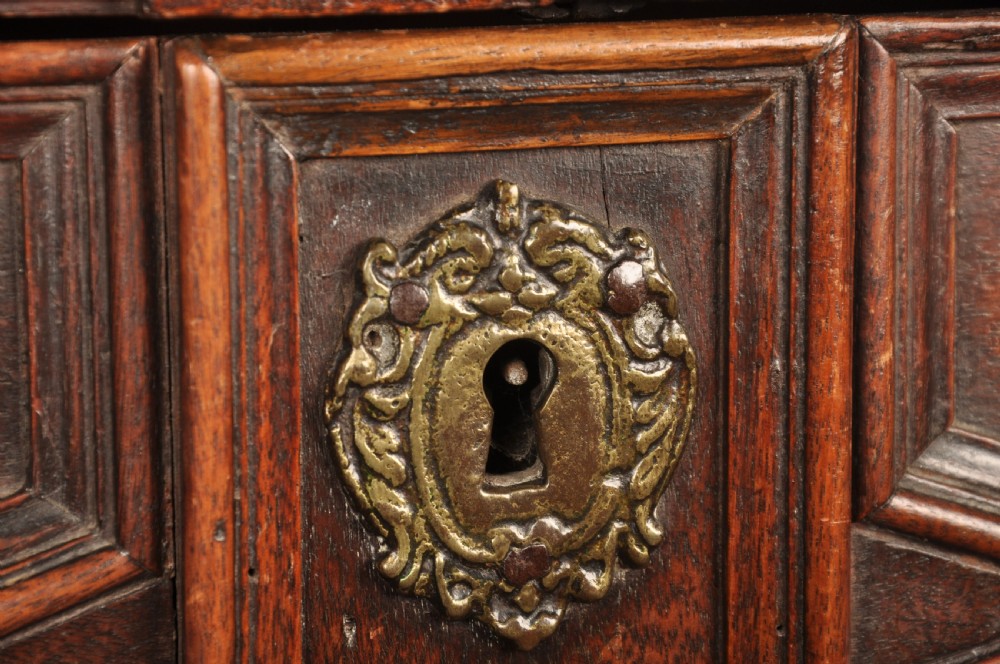 A 17th-century Charles II walnut and fruitwood chest of drawers featuring geometric mitred panels and brass keyhole escutcheons. View VIII