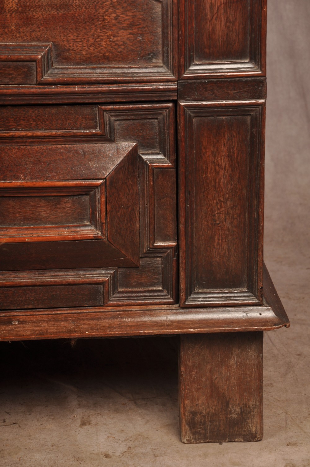 A 17th-century Charles II walnut and fruitwood chest of drawers featuring geometric mitred panels and brass keyhole escutcheons. View IX