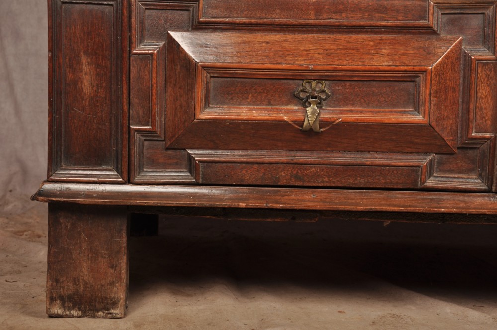 A 17th-century Charles II walnut and fruitwood chest of drawers featuring geometric mitred panels and brass keyhole escutcheons. View X