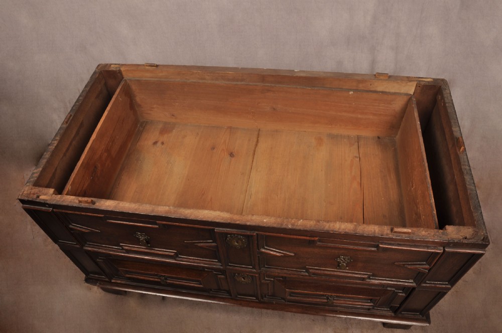 A 17th-century Charles II walnut and fruitwood chest of drawers featuring geometric mitred panels and brass keyhole escutcheons. View XVI