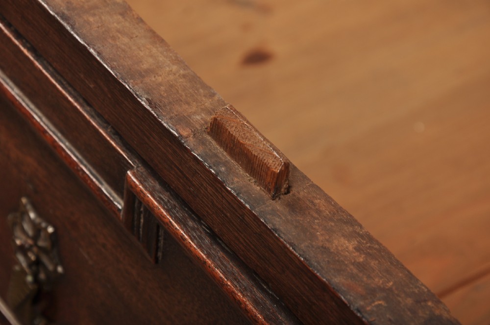 A 17th-century Charles II walnut and fruitwood chest of drawers featuring geometric mitred panels and brass keyhole escutcheons. View XVII