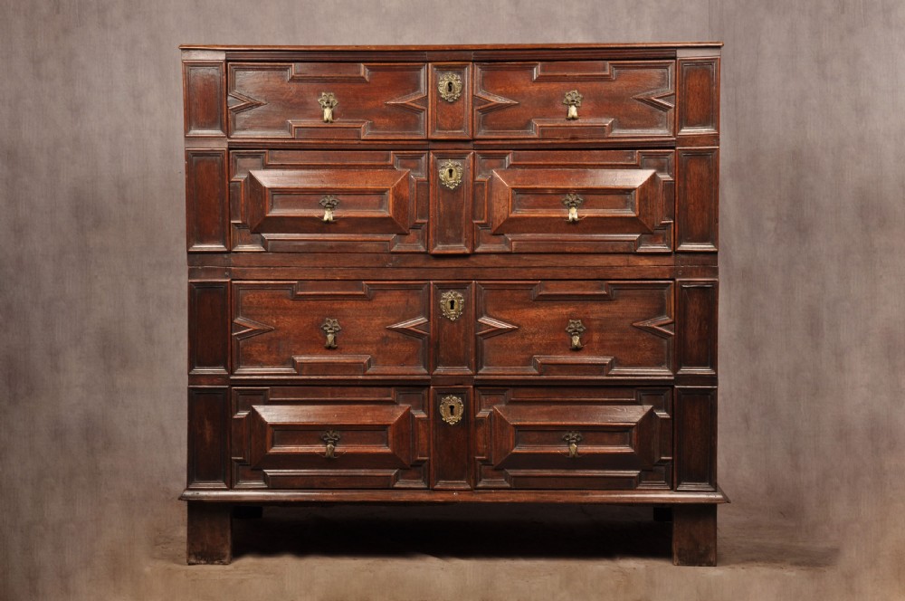 A 17th-century Charles II walnut and fruitwood chest of drawers featuring geometric mitred panels and brass keyhole escutcheons. View XX