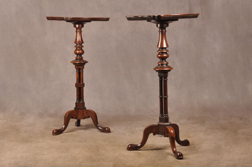 A pair of dark rosewood pedestal stands featuring turned baluster shafts, shaped tops, and tripod bases with pad feet.