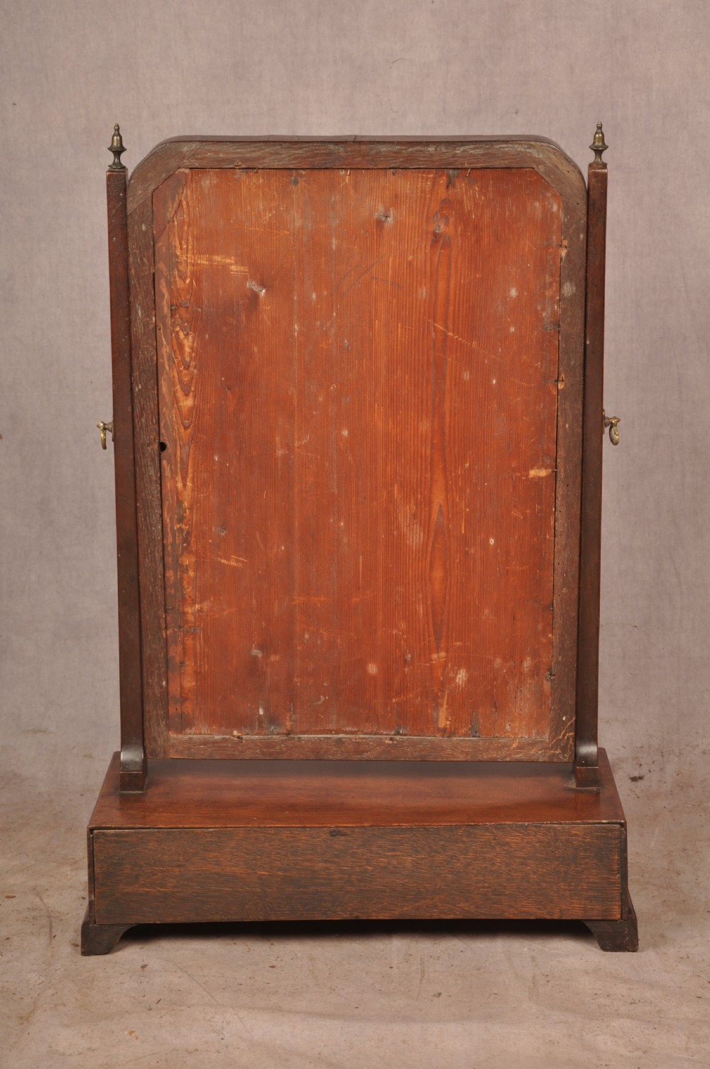 An 18th-century mahogany toilet mirror featuring an adjustable glass plate surrounded by a gilt slip, supported by vertical uprights with brass finials over a single-drawer plinth base. View VIII