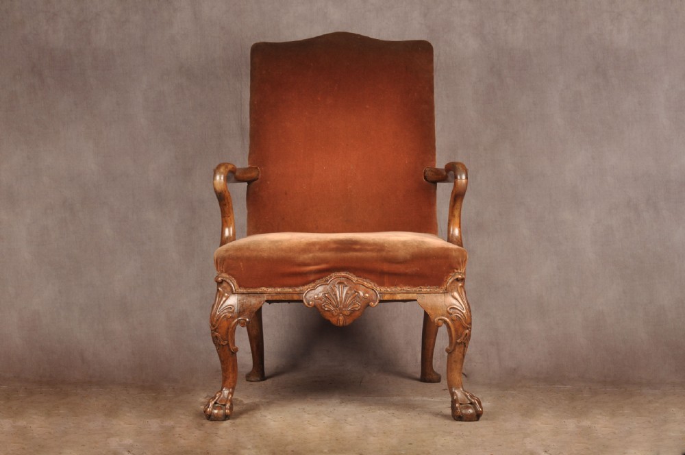 A 19th-century walnut library armchair upholstered in terracotta velvet with carved cabriole legs and claw and ball feet.