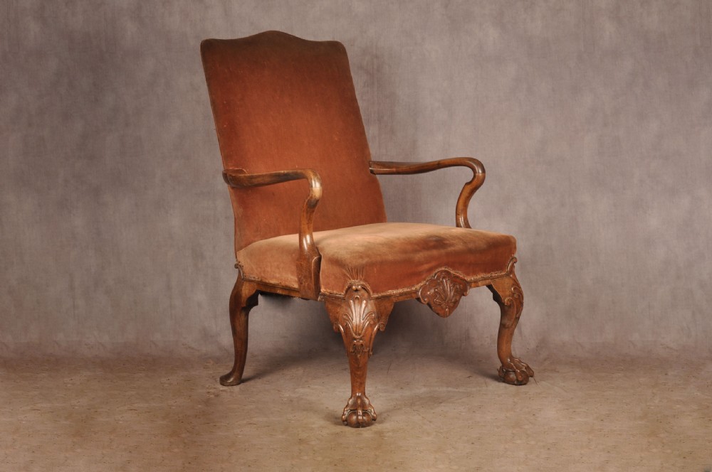 A 19th-century walnut library armchair upholstered in terracotta velvet with carved cabriole legs and claw and ball feet. View IV