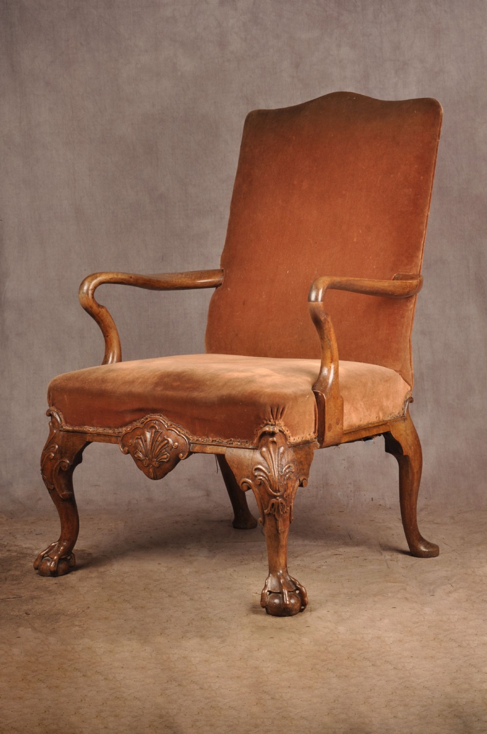 A 19th-century walnut library armchair upholstered in terracotta velvet with carved cabriole legs and claw and ball feet. View V