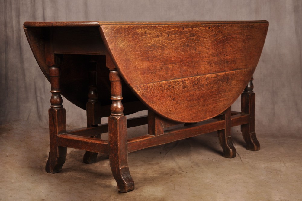 An 18th-century oak gateleg dining table with folded drop leaves, turned legs, and square stretchers.