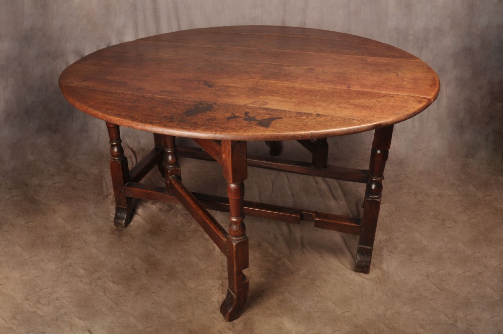 An 18th-century oak gateleg dining table with folded drop leaves, turned legs, and square stretchers. View II