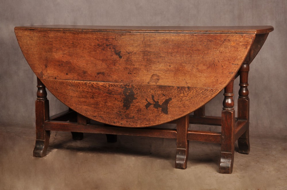 An 18th-century oak gateleg dining table with folded drop leaves, turned legs, and square stretchers. View V