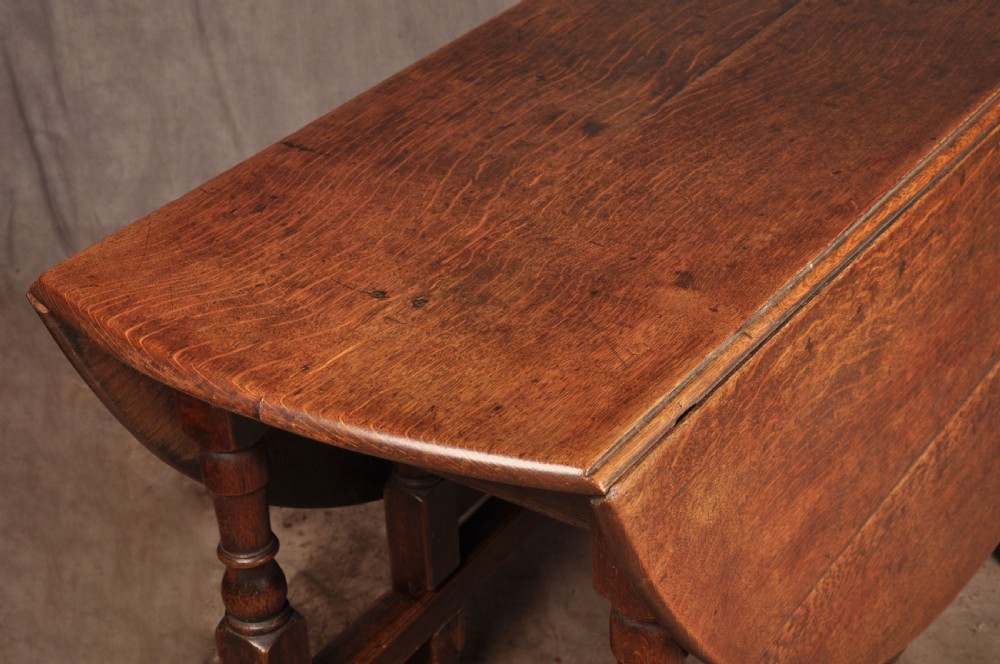 An 18th-century oak gateleg dining table with folded drop leaves, turned legs, and square stretchers. View VI