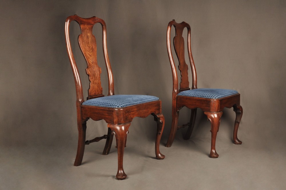 A pair of George I mahogany side chairs featuring vase-shaped back splats, blue patterned drop-in seats, and cabriole front legs.