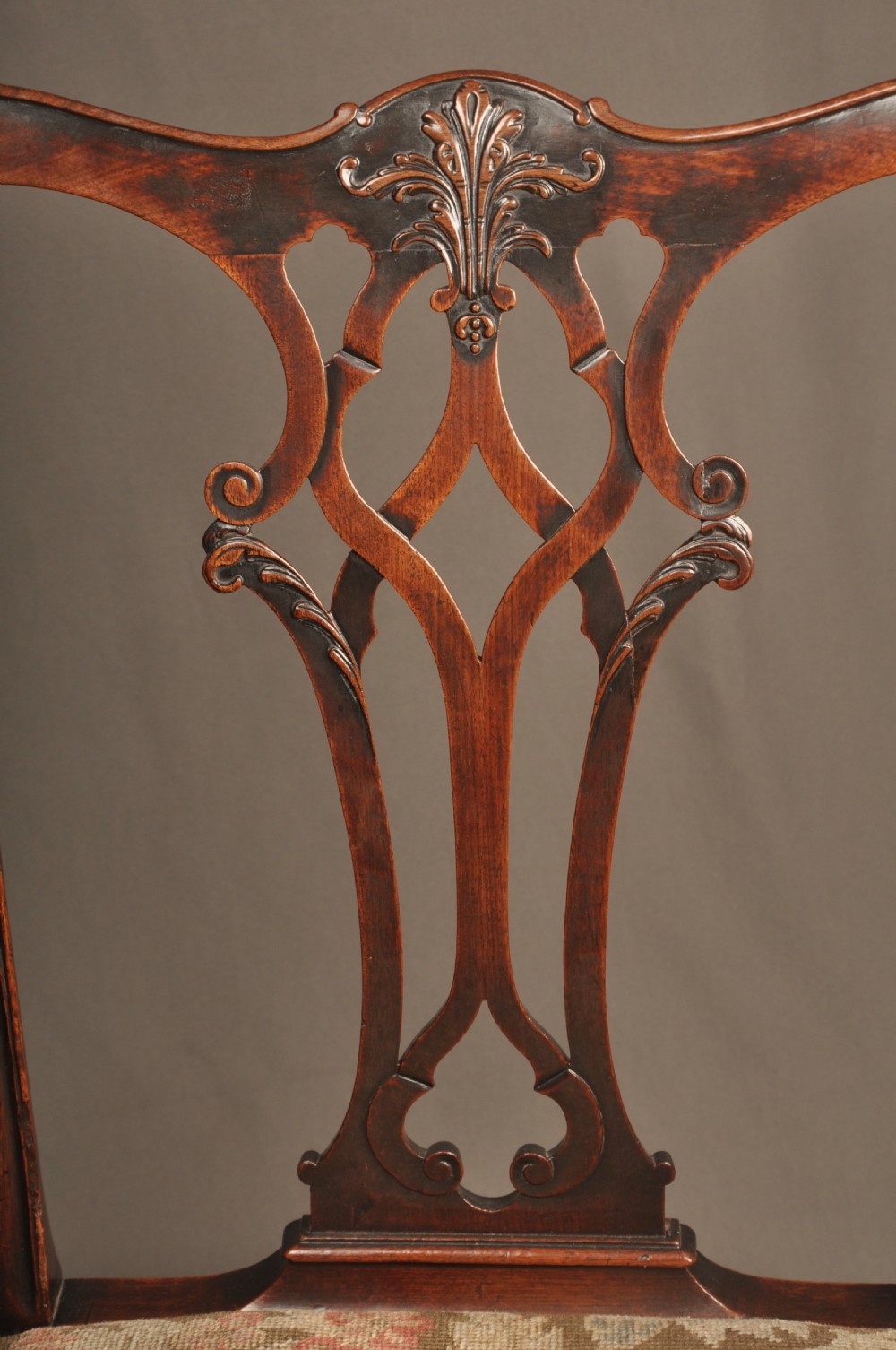 An 18th-century Chippendale mahogany armchair featuring a carved pierced splat back, swept armrests, an upholstered drop-in seat, and square legs joined by H-stretchers. View V
