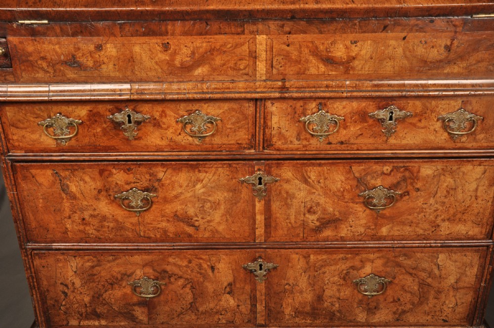 An eighteenth-century Queen Anne burr walnut bureau with a sloping fall-front lid above drawers featuring brass drop handles, resting on bracket feet. View IV
