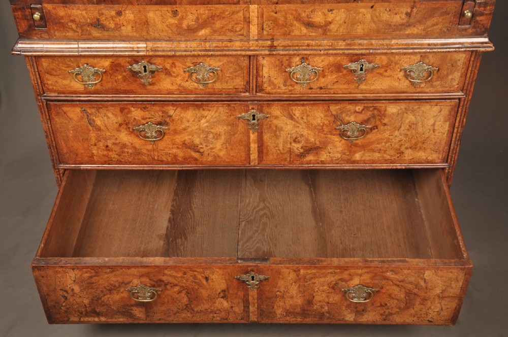 An eighteenth-century Queen Anne burr walnut bureau with a sloping fall-front lid above drawers featuring brass drop handles, resting on bracket feet. View V