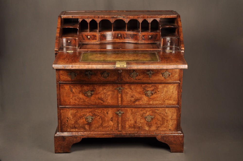 An eighteenth-century Queen Anne burr walnut bureau with a sloping fall-front lid above drawers featuring brass drop handles, resting on bracket feet. View VIII