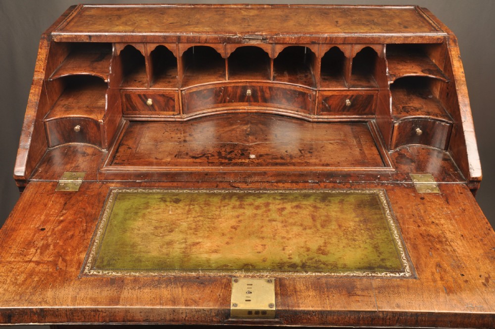 An eighteenth-century Queen Anne burr walnut bureau with a sloping fall-front lid above drawers featuring brass drop handles, resting on bracket feet. View IX