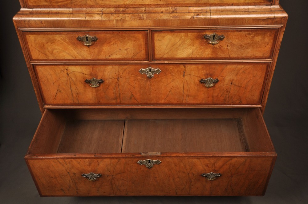 A tall Queen Anne walnut chest on chest featuring two stacked sections of drawers with brass handles and bracket feet. View VII