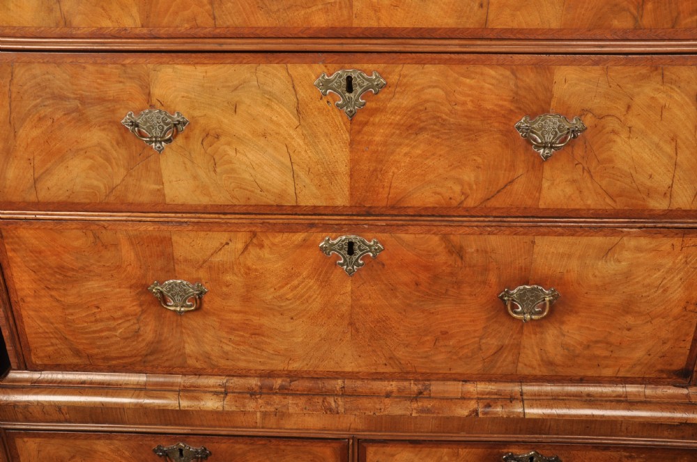 A tall Queen Anne walnut chest on chest featuring two stacked sections of drawers with brass handles and bracket feet. View IX