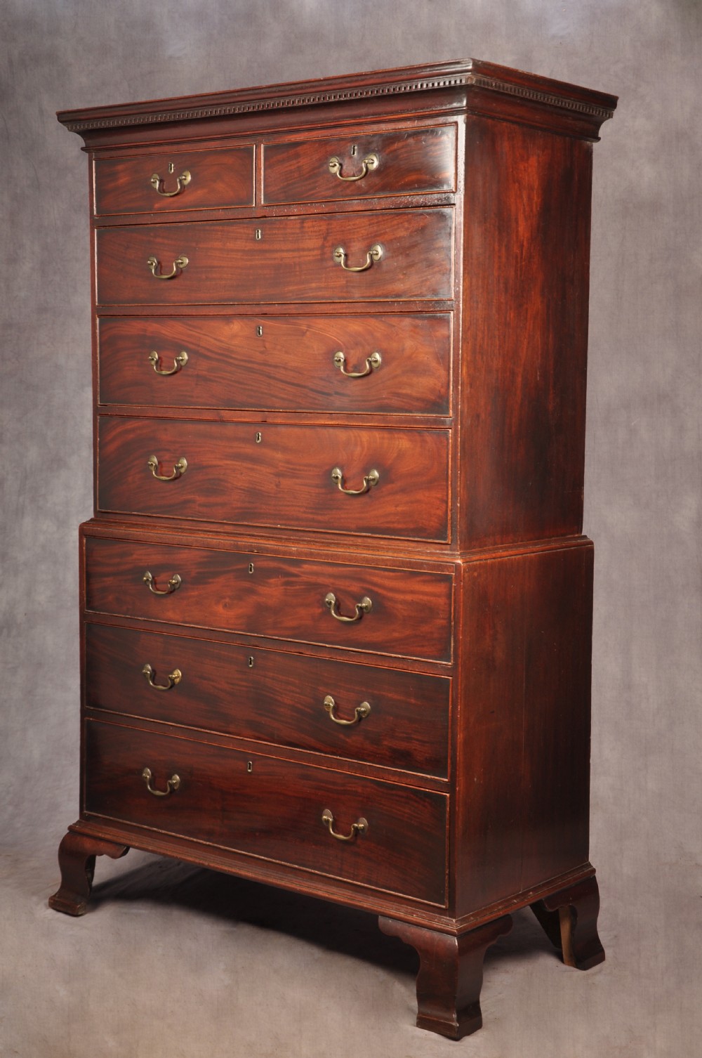 An 18th-century Georgian mahogany chest-on-chest featuring a two-part construction with brass swan-neck handles and bracket feet.