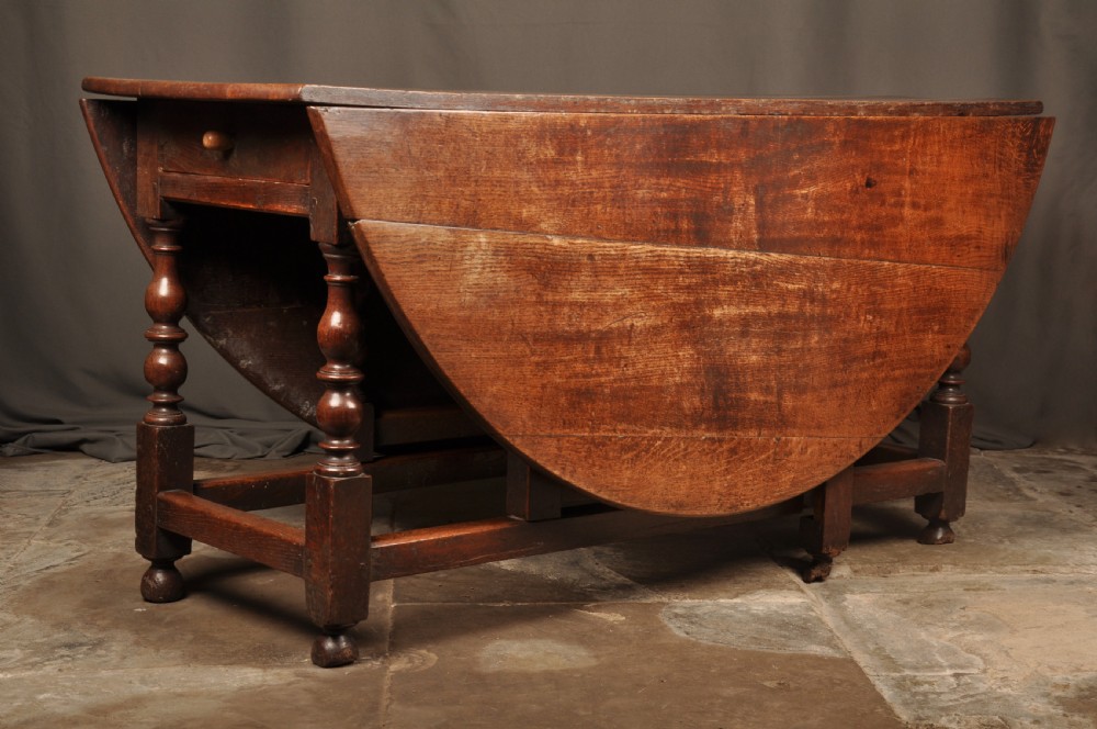 A large 17th-century solid oak gateleg dining table featuring drop leaves, turned legs, and perimeter stretchers. View II