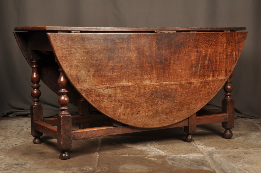 A large 17th-century solid oak gateleg dining table featuring drop leaves, turned legs, and perimeter stretchers. View III