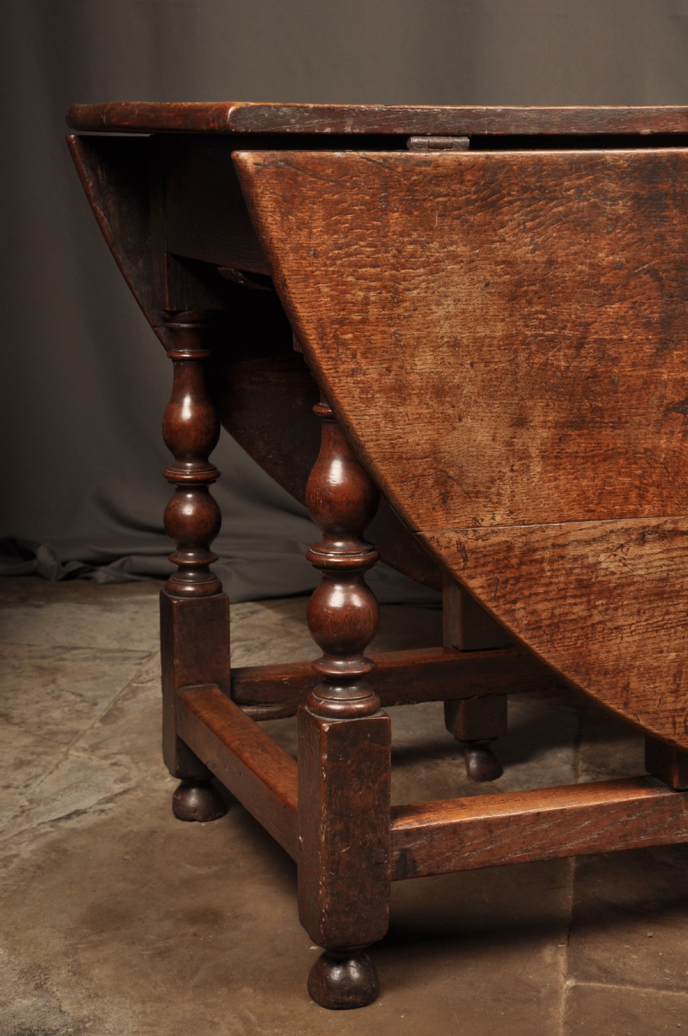 A large 17th-century solid oak gateleg dining table featuring drop leaves, turned legs, and perimeter stretchers. View V